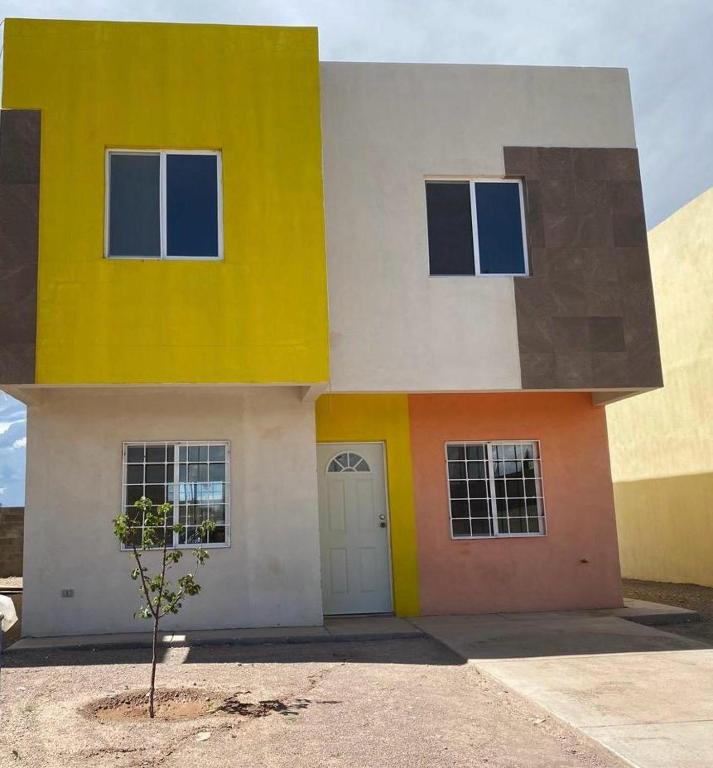 a yellow and white house with a tree in front of it at Your modern getaway with uniquely stylish comfort in Nuevo Casas Grandes