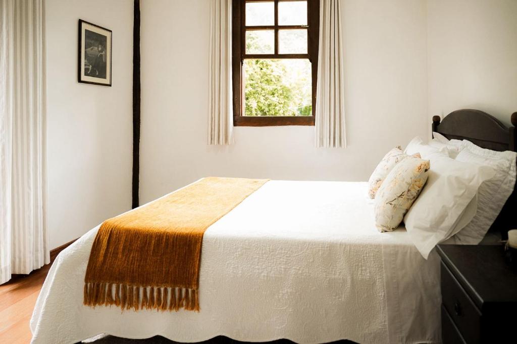 a bedroom with a white bed with a window at Pousada do Nonno in Venda Nova do Imigrante