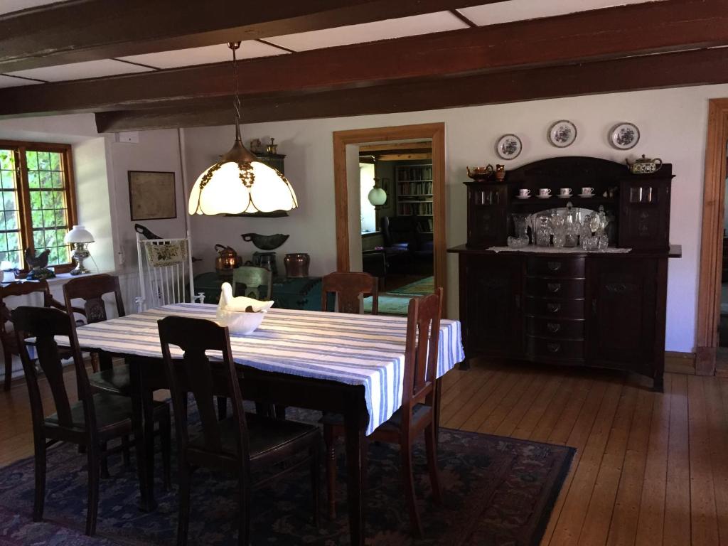 a dining room with a table and chairs and a kitchen at Björkåsa Gård Bed & Box in Annelöv