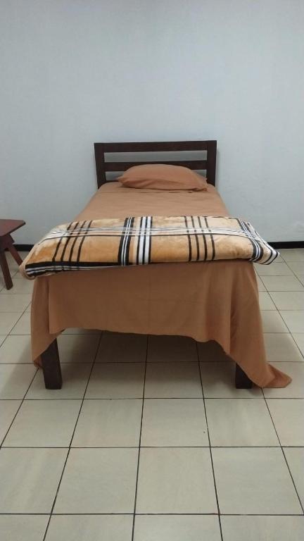a bed sitting on a tiled floor in a room at Hostal Travesía Urbana in Guadalupe