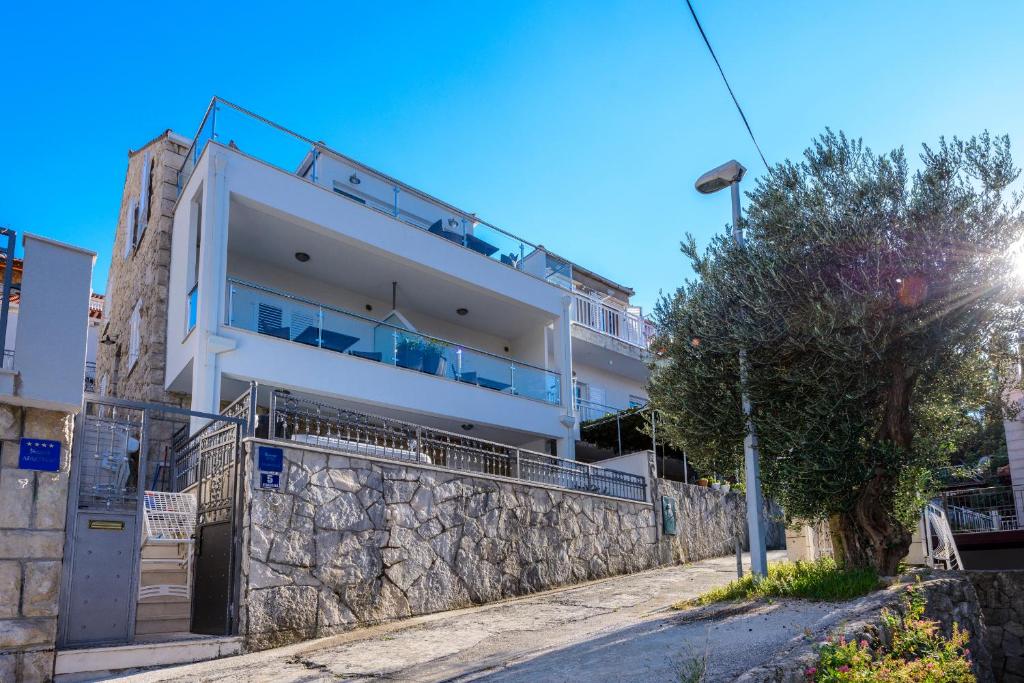 a large building with a stone wall and a tree at Apartments Niko in Cavtat