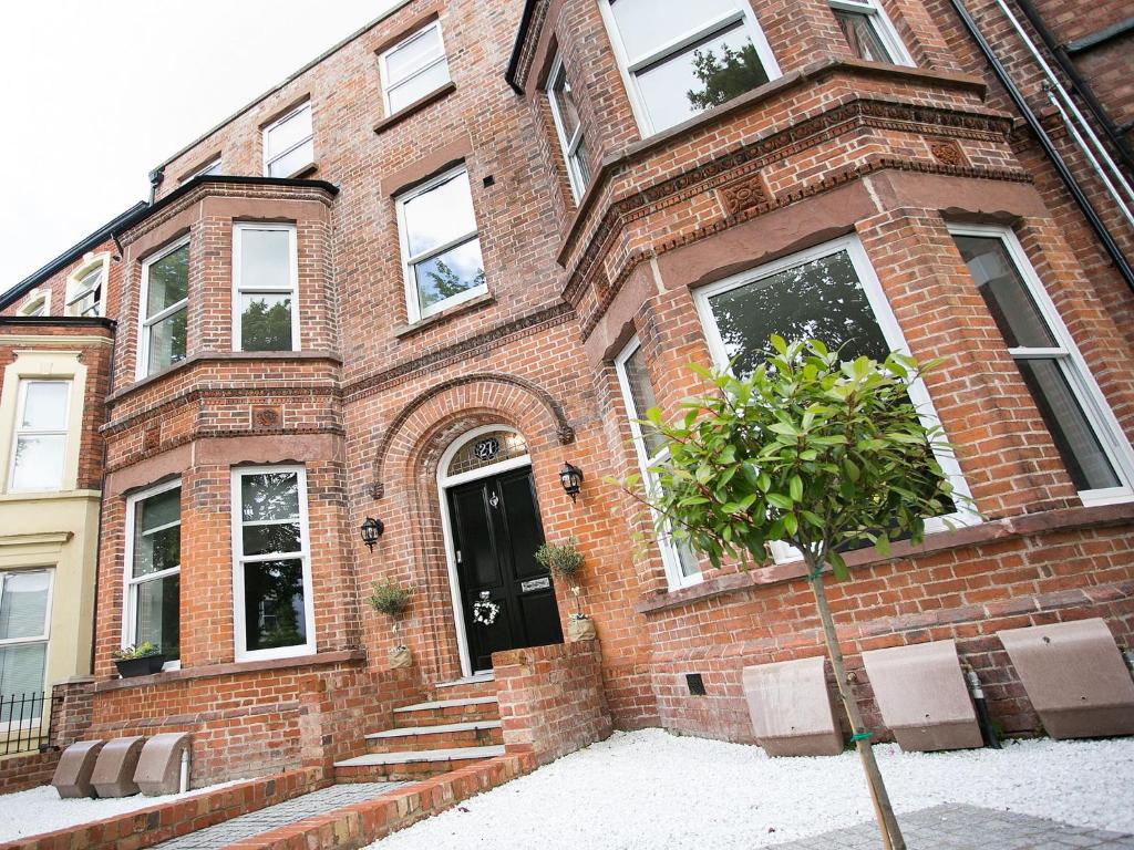 een stenen huis met een boom ervoor bij Queens Quarter Apartments in Belfast