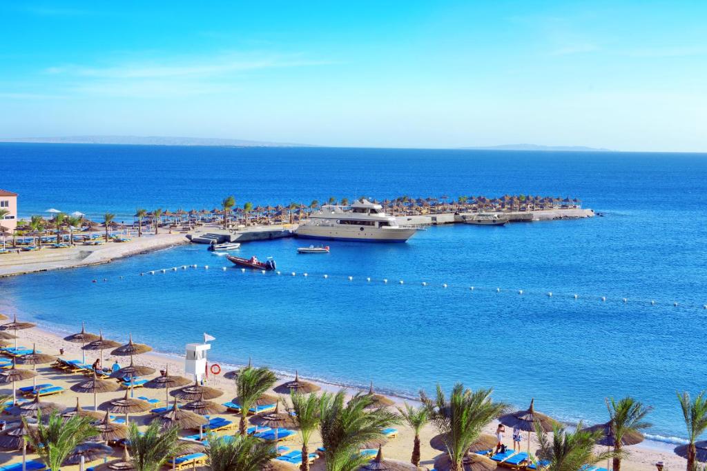 Beach Albatros Aqua Park - Hurghada في الغردقة: شاطئ به ناس وسفينة بحرية في الماء