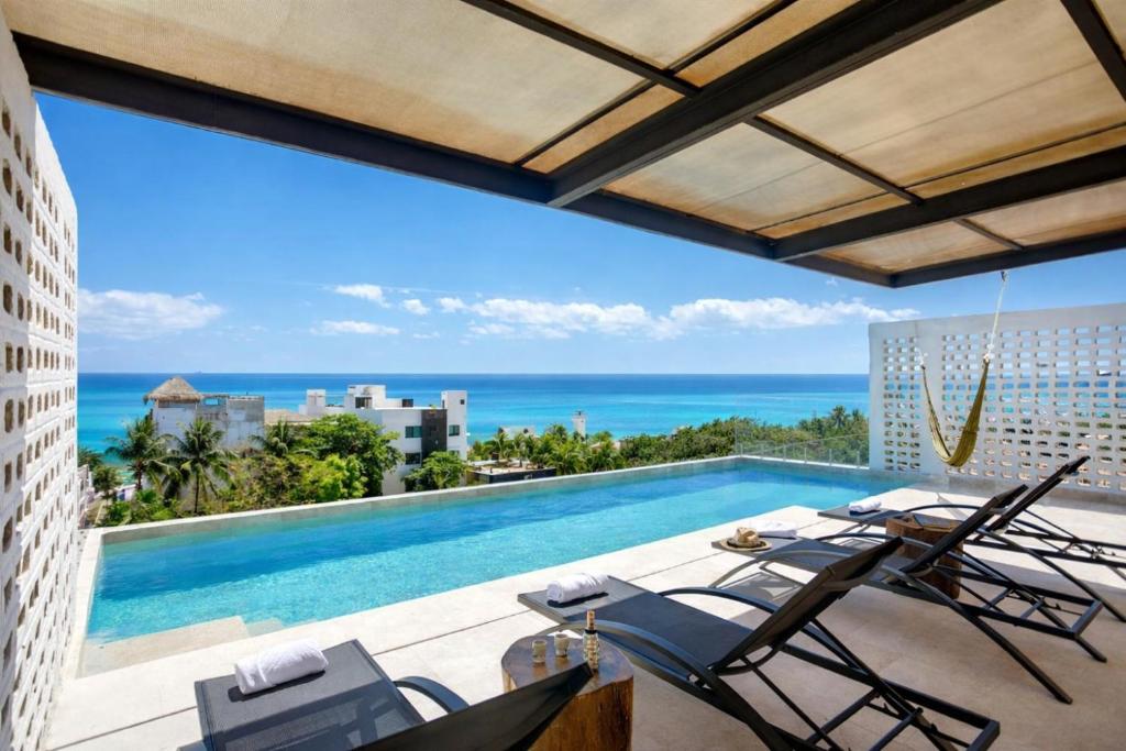 a view of a pool and the ocean from a building at Lalola DownTown Boutique Apartments in Puerto Morelos