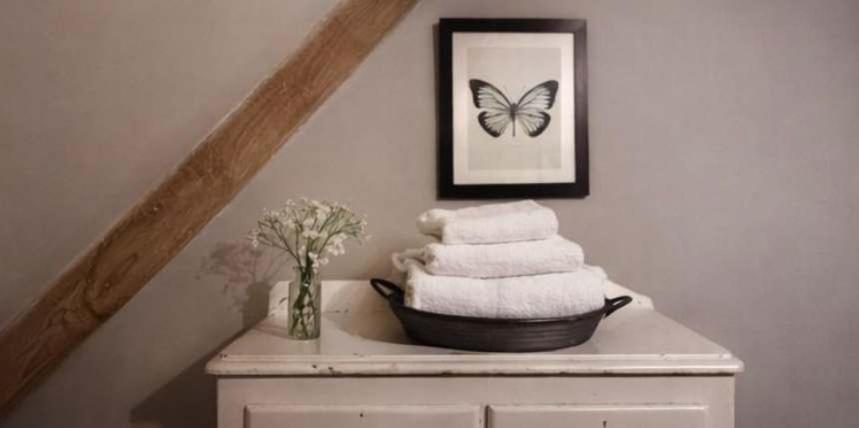 a pile of towels on top of a table with a butterfly at Jasmine Cottage, Upper Slaughter, Cotswolds in Cheltenham
