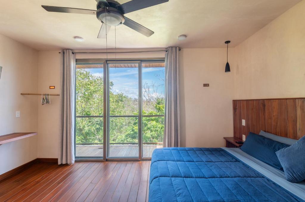 a bedroom with a blue bed and a large window at Master Jungle Penthouse with Large Private Terrace - Santuario Hotel Boutique in Chemuyil