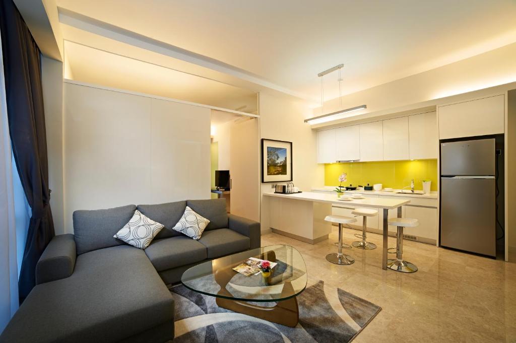 A lounge-and-kitchen view of a serviced suite with a large sofa and breakfast counter.