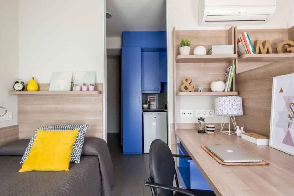 a living room with a couch and a desk with a laptop at Colegio Mayor La Concepción in Valencia