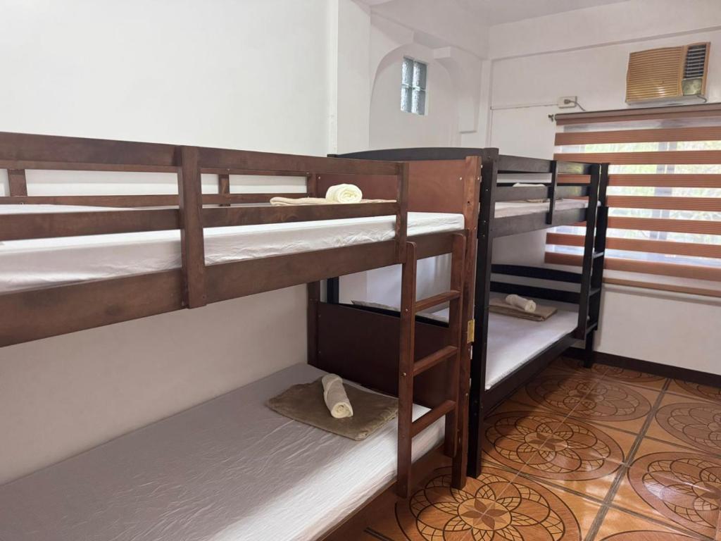 a room with three bunk beds in a room at Mabel's Garden Stay in Puerto Galera