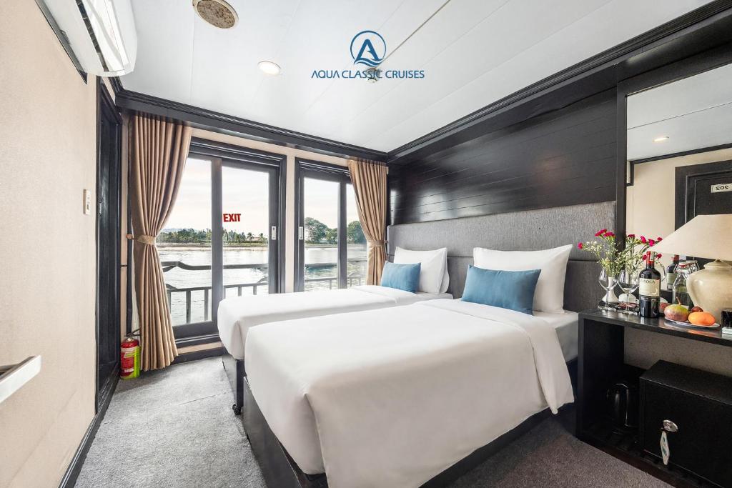 a hotel room with two beds and a balcony at Aqua Classic Cruise in Ha Long