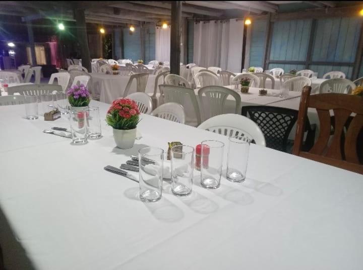 a white table with glasses and flowers on it at El Atardecer in Lunarejo
