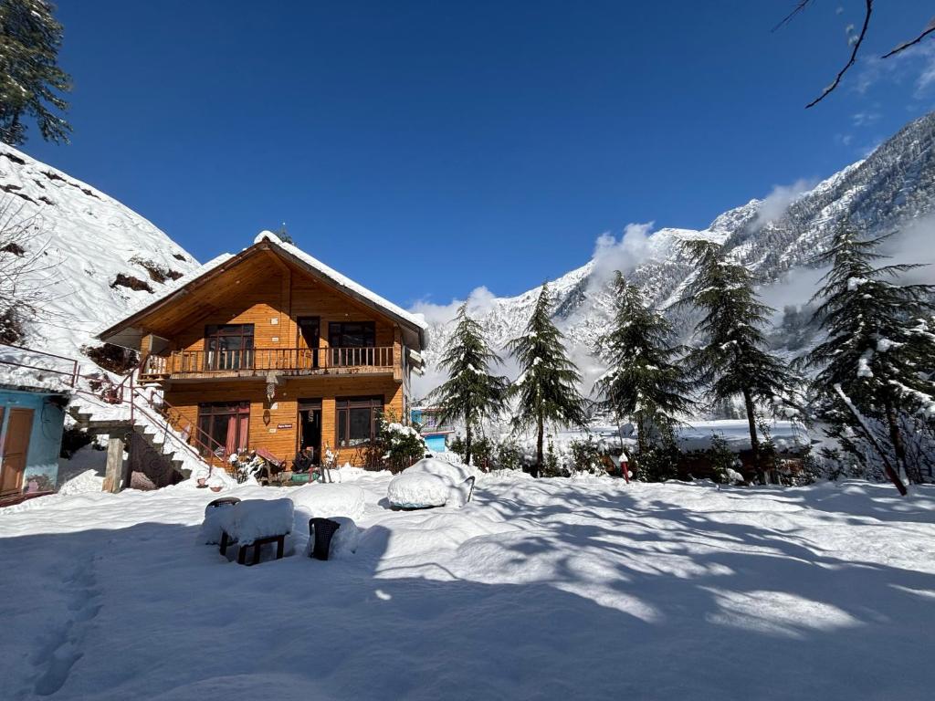 a log cabin in the snow in front of a mountain at Alpine Homes by Kayal Wood in Kulu
