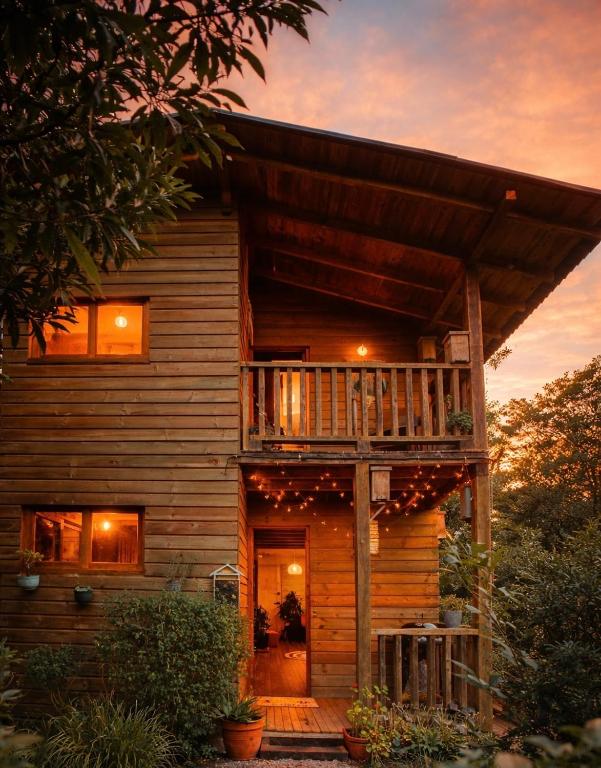 a wooden house with a deck with a balcony at Beehouse Arví Cabaña in Guarne
