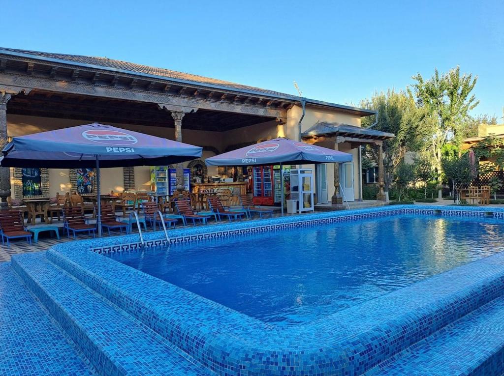 a swimming pool with two umbrellas and a restaurant at Hotel Asia Khiva in Khiva