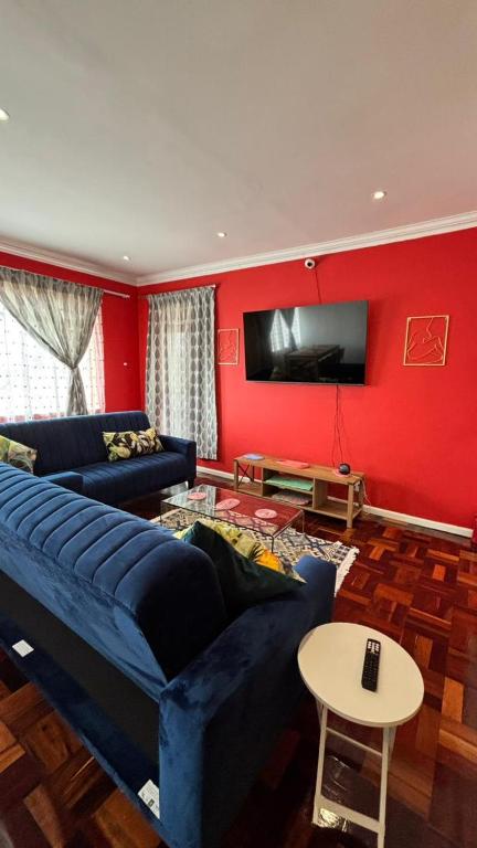 a living room with a blue couch and a red wall at Two Sixty Nine in Gqeberha