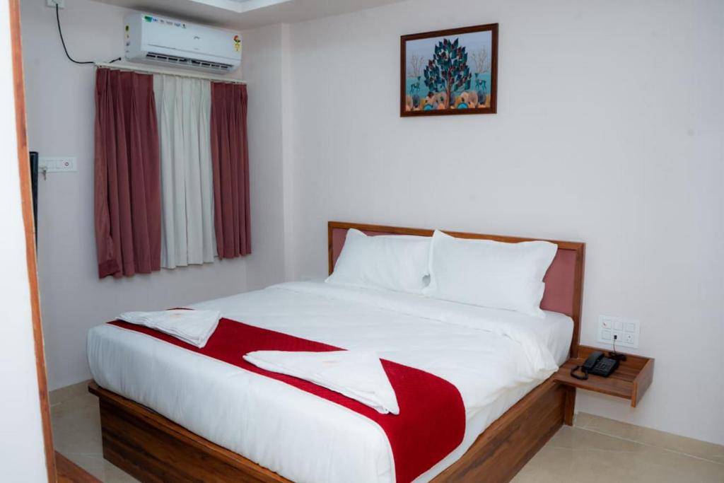 a bedroom with a bed with a red and white blanket at THE RAMA Executive in Tuljapur