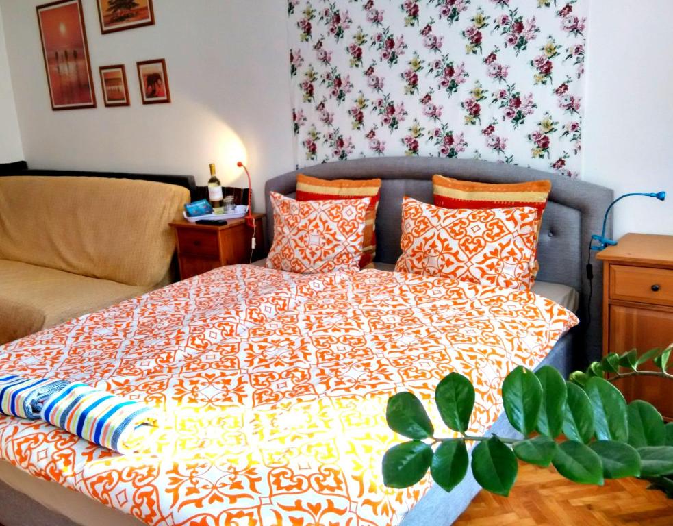 a bedroom with a bed with a orange and white comforter at BZE Apartment in Budapest