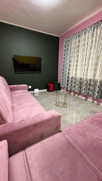 a living room with a pink couch and a tv at One Thirty Six in Gqeberha