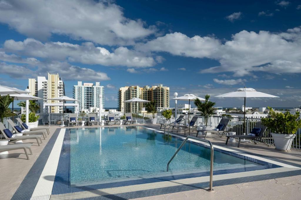 a swimming pool with chairs and umbrellas on a building at Courtyard Miami Beach South Beach in Miami Beach