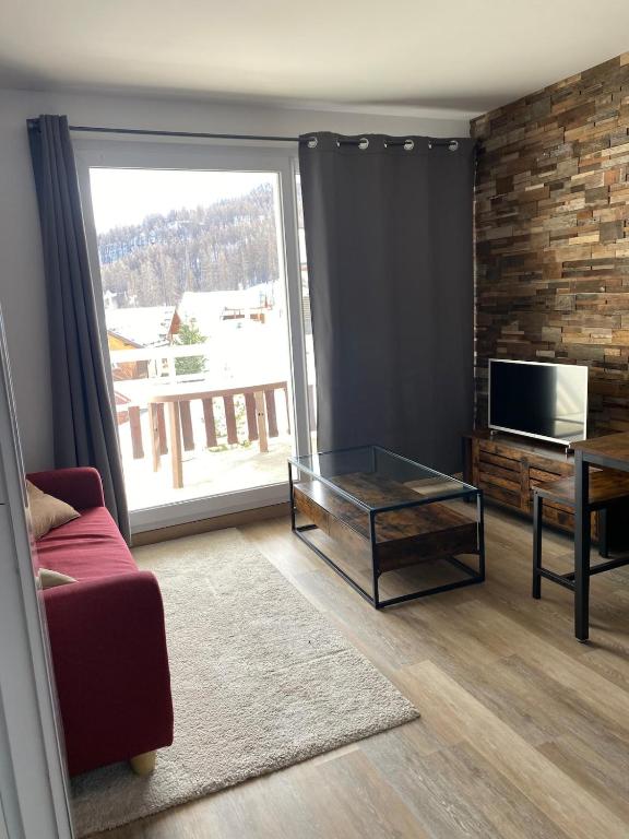 a living room with a glass coffee table and a television at 2 Chambres Centre Station 1600 in Puy-Saint-Vincent