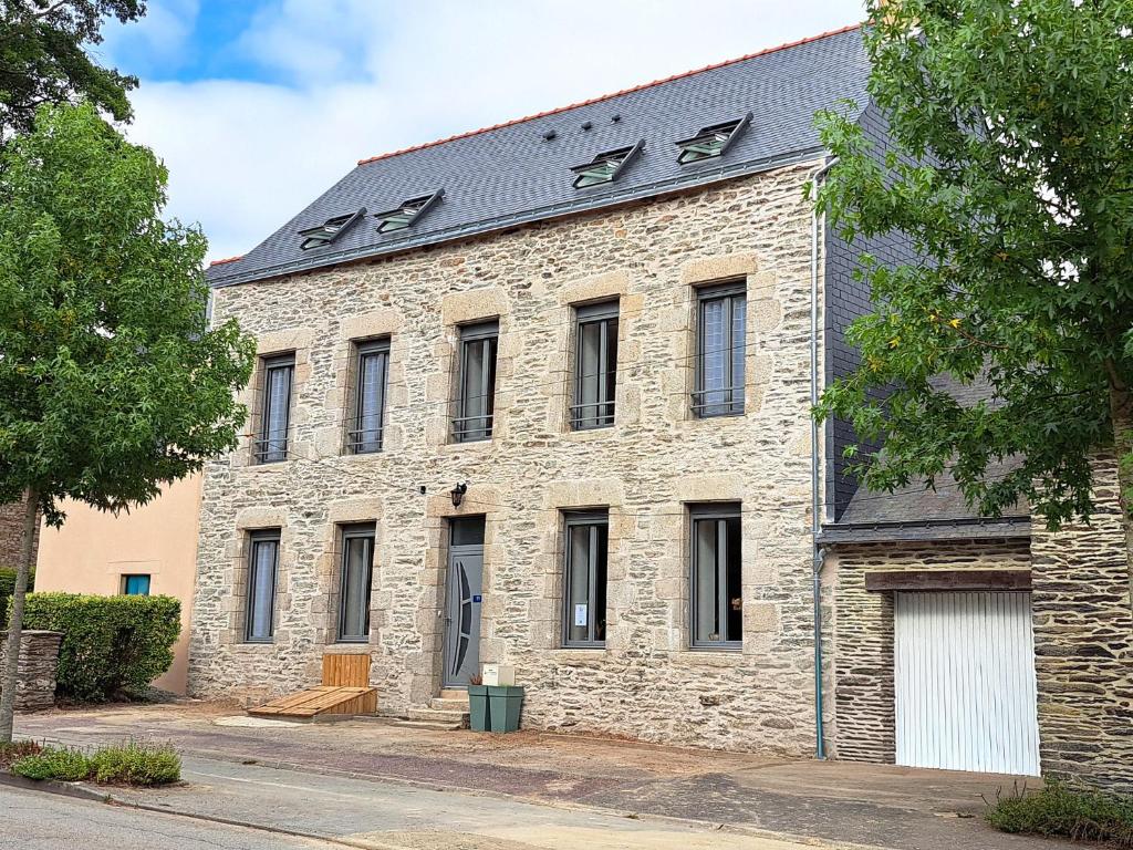 an old stone building with a black roof at Le Foyer Celtique in Ploërmel