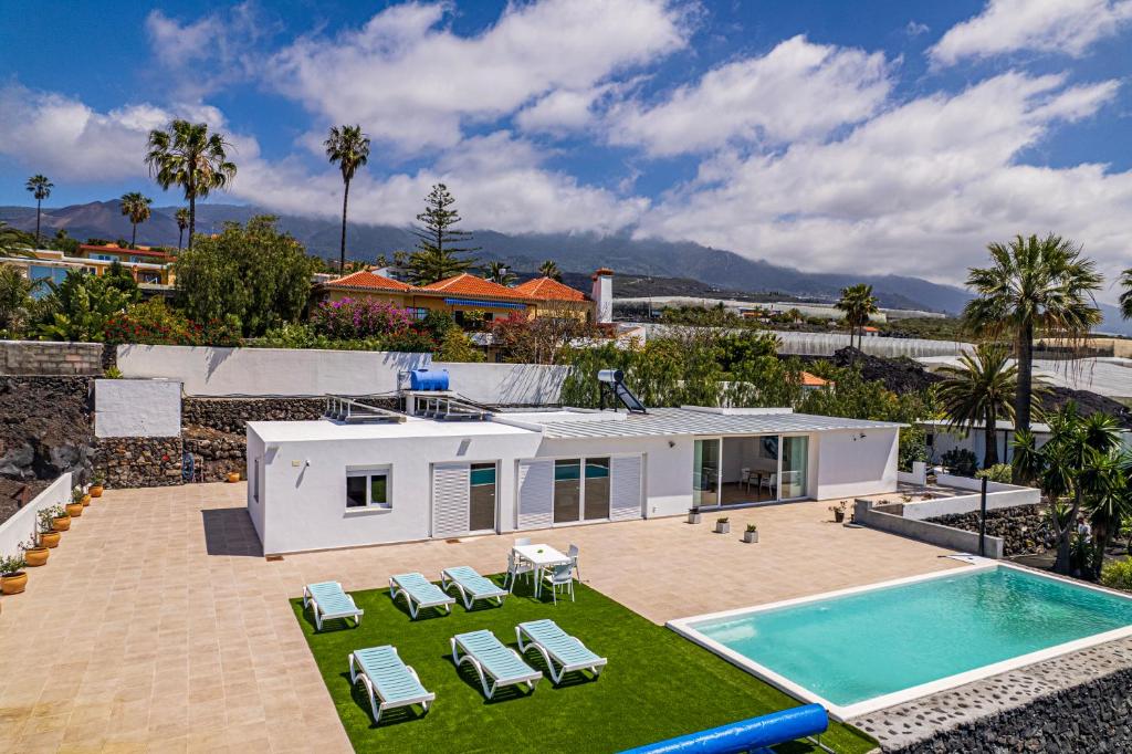 a house with a swimming pool and some chairs and a house at Villa Las Norias in Tazacorte
