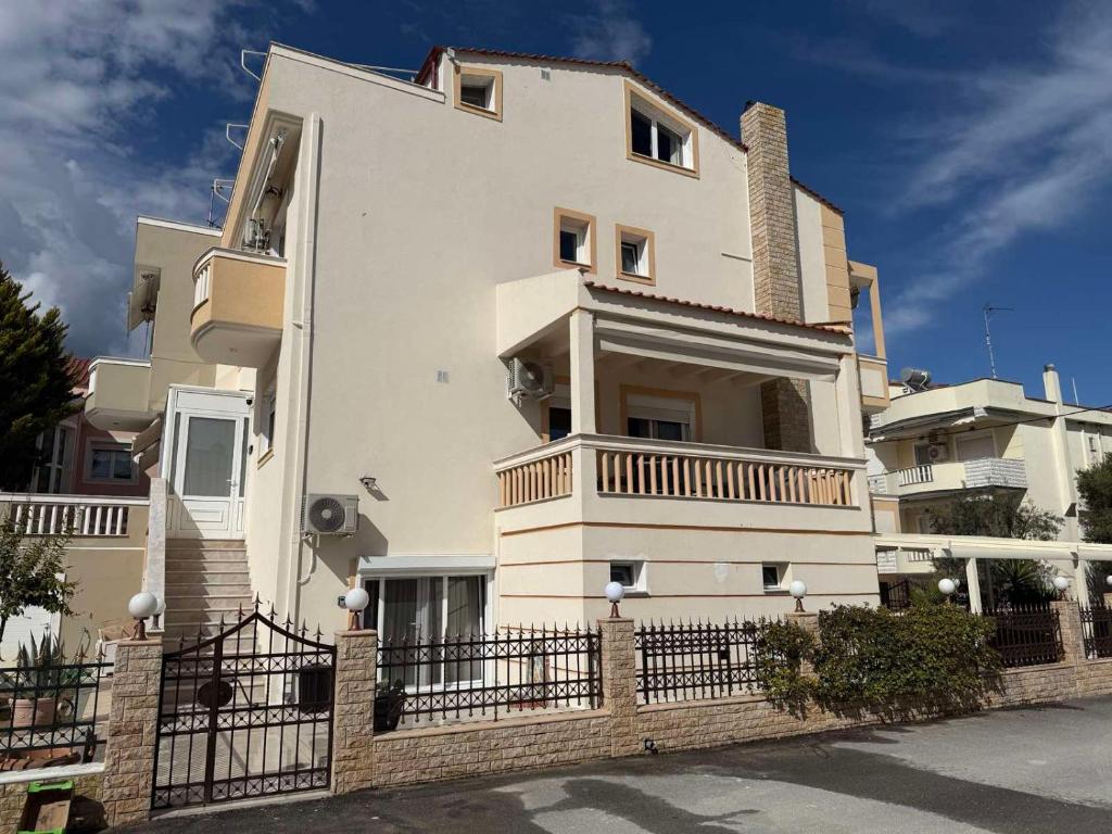 a white building with a fence in front of it at Villa Sunrice in Nea Peramos