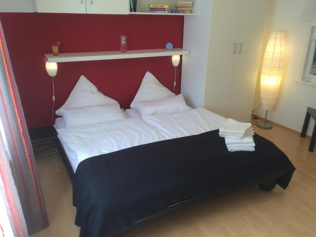 Schlafzimmer mit einem Bett mit rotem Kopfteil und weißen Kissen in der Unterkunft Apartments Stadtmauer in Northeim