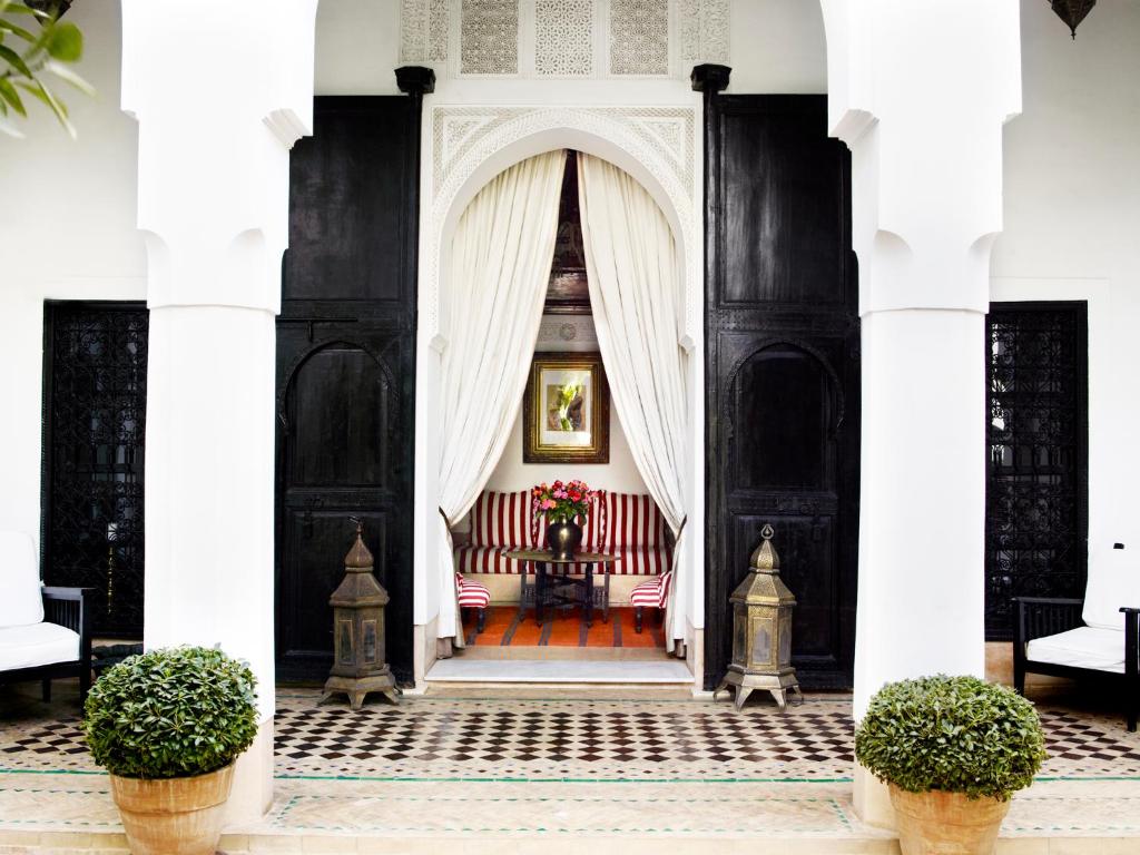 a black and white house with a red bench in the doorway at Riad L'Hôtel Marrakech in Marrakesh