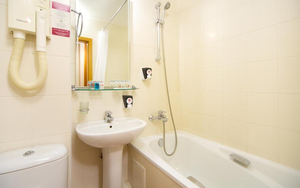 a bathroom with a sink and a toilet and a bath tub at AZIMUT Hotel Siberia in Novosibirsk