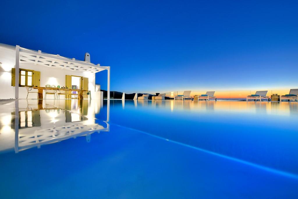 a swimming pool with a house on the water at Mykonos Ark Villas in Elia