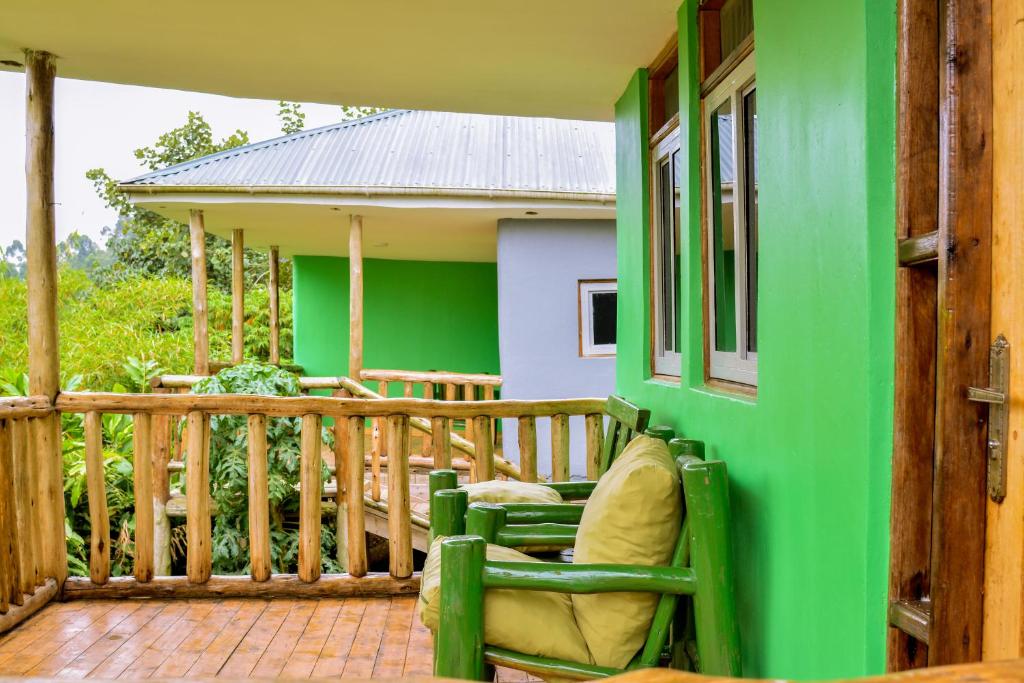 a green house with a chair on a porch at Bwindi Breeze Lodge in Kisoro