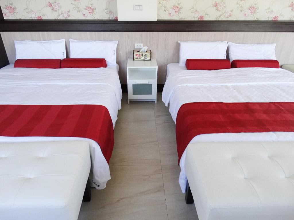 two beds in a room with red and white sheets at Ikegami Dapo Moutain Bed and Breakfast in Chishang