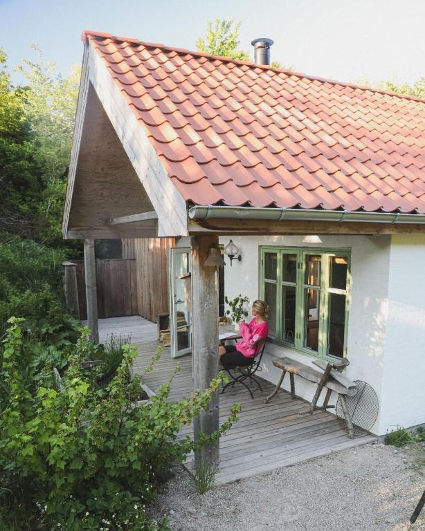 a woman sitting on the porch of a house at Koppes Mølle B&B - naturnær overnatning in Borup