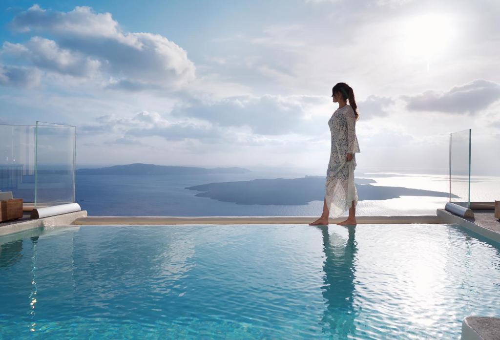 a woman standing on the edge of a swimming pool at Villa Ioli Anastasia in Firostefani
