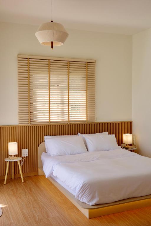 a bedroom with a large white bed and a window at Yugen House - Yuma in Nong Prue