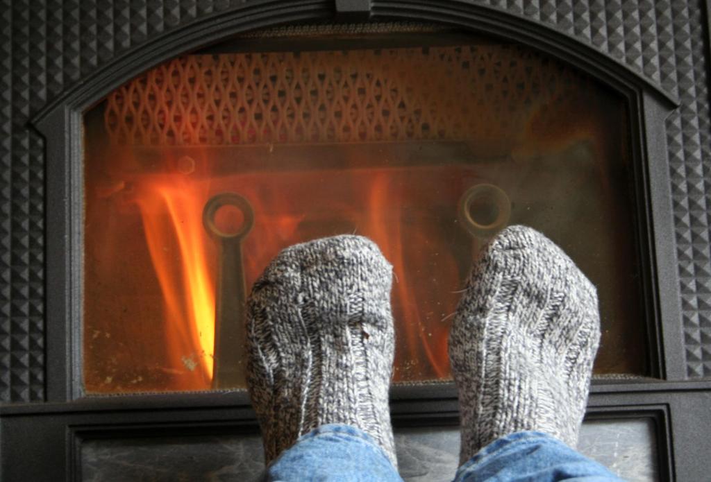 a person with their feet up in front of a fireplace at Dale Farm Holidays in Hunmanby