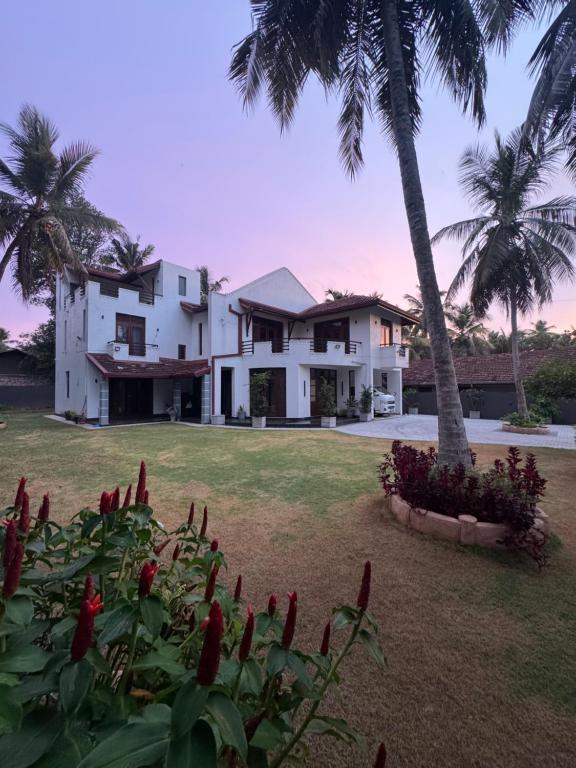 a house with palm trees and red flowers in front of it at Perera Tree Villa in Ja-Ela