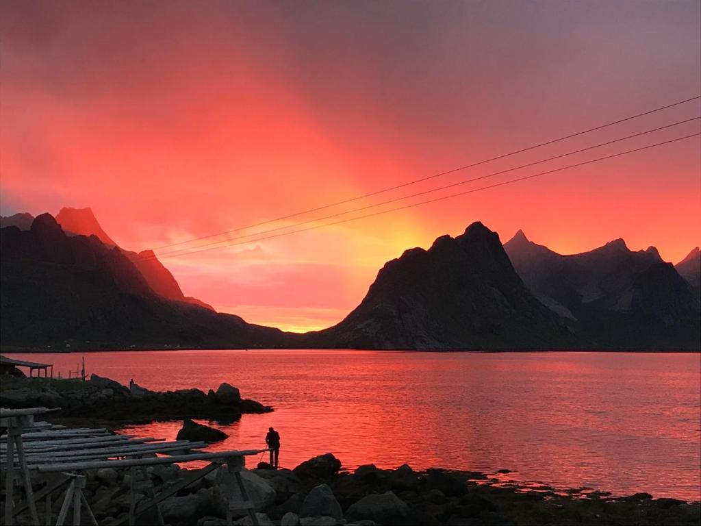 a person standing on the shore of a lake at sunset at Villa valen, Reine in Moskenes