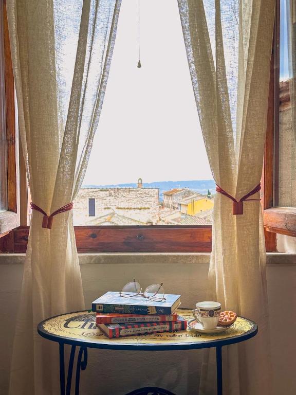 a table with books on it next to a window at Cozy 18th century house in San Gimignano