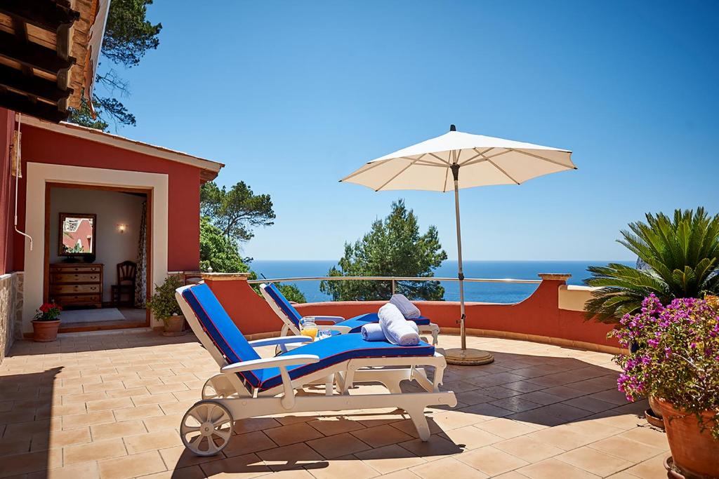 a pair of chairs and an umbrella on a patio at Las Escaleras - Villa SIKA - 4S in Port d'Andratx