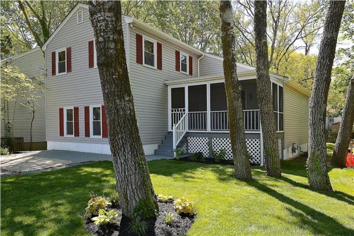 a white house with red windows and a group of trees at Relaxing Beginnings in Cape May Point