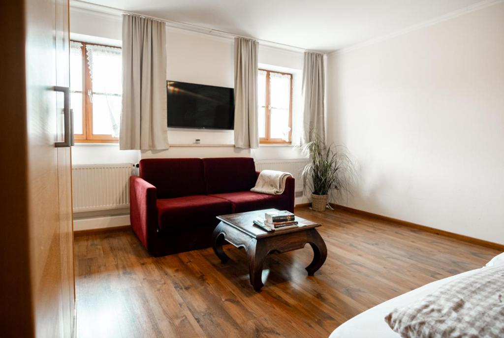 a living room with a red couch and a coffee table at Ferienwohnungen Steinbacher in Vogtareuth