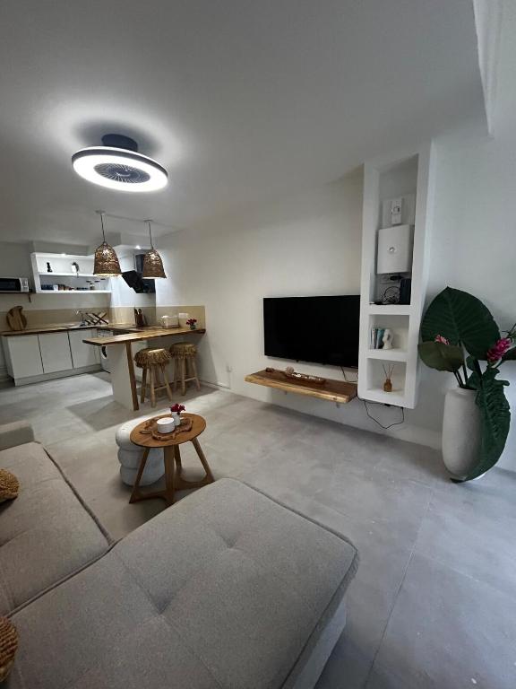 a living room with a flat screen tv and a table at Charmant Appartement Grand Gosier in Le Gosier