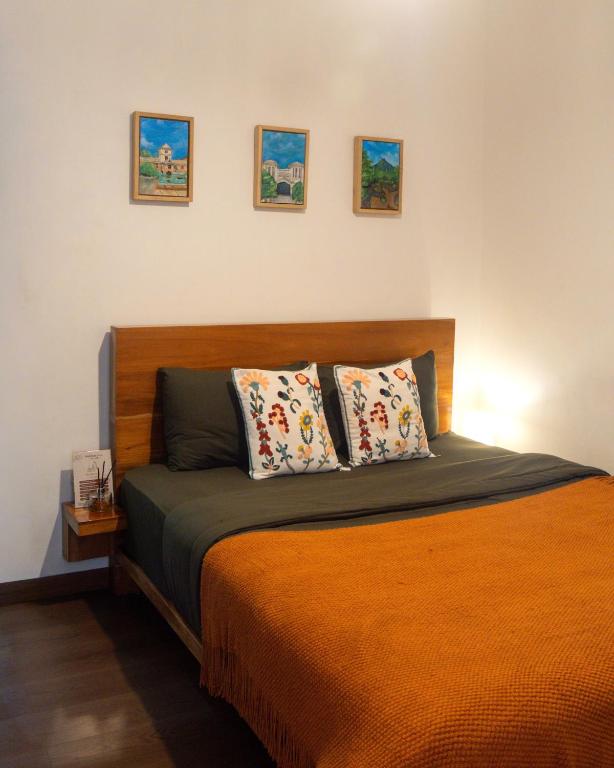 a bedroom with a bed with three pictures on the wall at Sukhayana Stay Malioboro in Yogyakarta