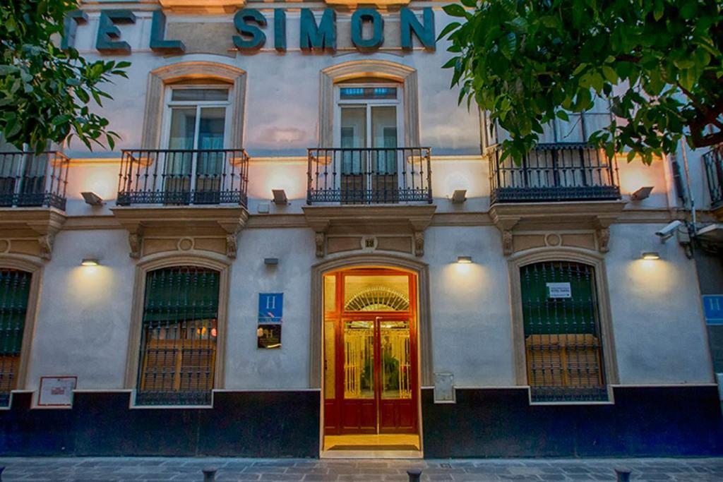 un bâtiment avec une porte rouge et un panneau sur celui-ci dans l'établissement Hotel Simon, à Séville