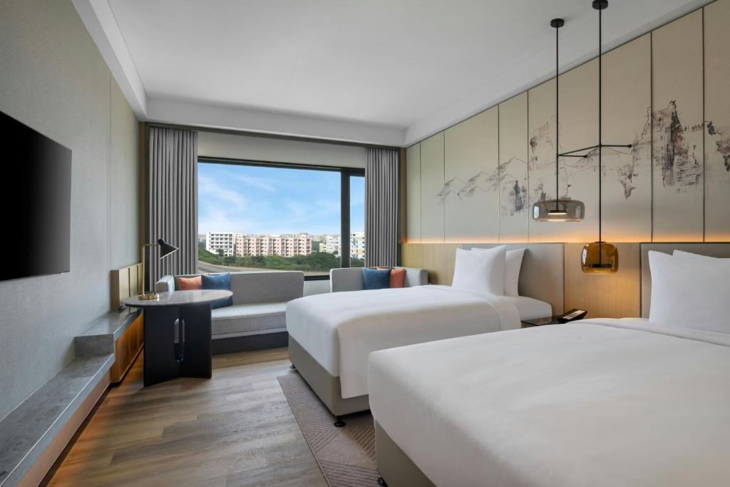 a hotel room with two beds and a couch at Courtyard By Marriott Tirupati in Tirupati