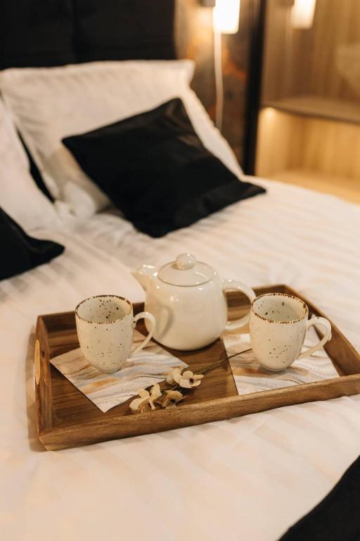 a tray with two cups and a tea pot on a bed at Apartman Prime - free parking in Belgrade