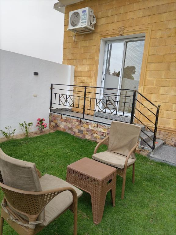 two chairs and a table on a lawn next to a house at realistic country guest house in Al Aqālitah