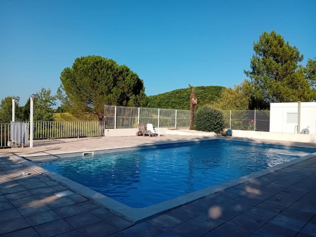 a swimming pool with blue water in a yard at Le Chalet de Pratviel - proche Albi in Puygouzon-et-Montsalvy